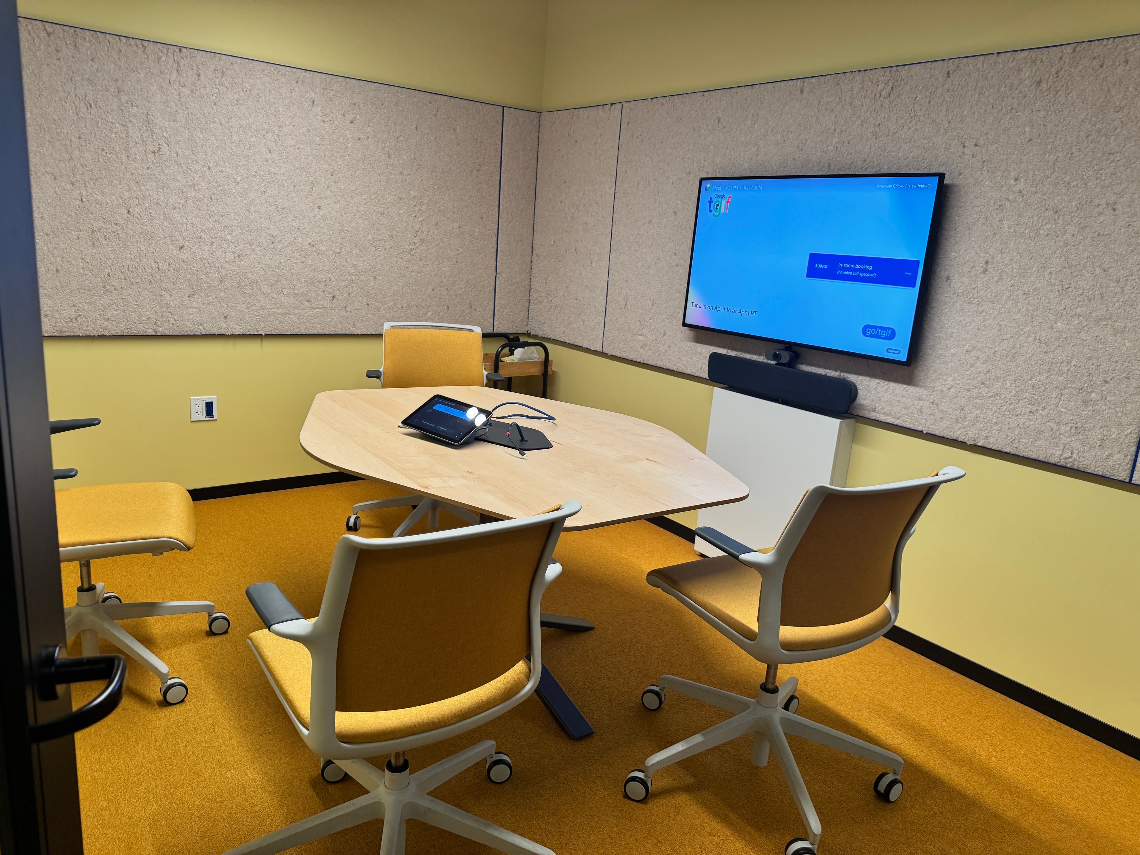 Small conference room with yellow chairs and display screen
